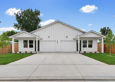 White duplex set against a blue sky and trees