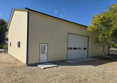 A beige metal shop with white doors set against a blue sky