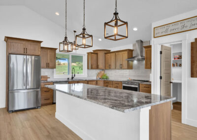 A bright and spacious kitchen with light wood cabinets and bright gray and beige swirled countertops